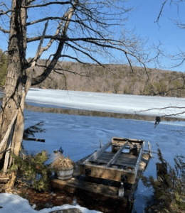 A dock floating on Percy Lake'sshore with ice melting in the distance.